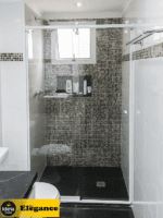 Box Elegance de vidro temperado incolor com estrutura metálica e roldanas aparentes na cor branco, sendo 1 folha fixa e 1 porta de correr.