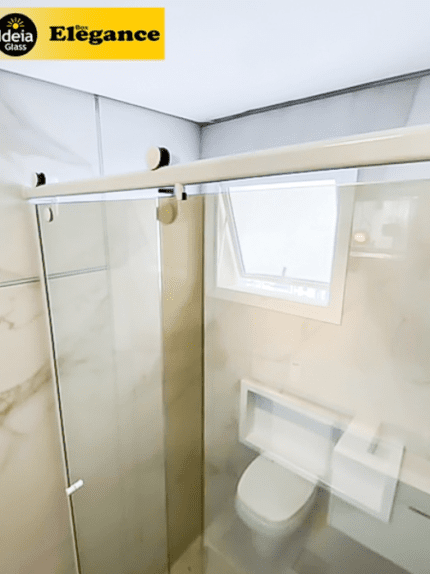 Box Elegance de vidro temperado incolor com estrutura metálica e roldanas aparentes na cor branco, sendo 1 folha fixa e 1 porta de correr.