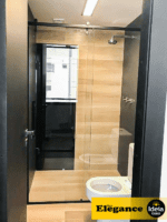 Box Elegance de vidro temperado incolor com estrutura metálica e roldanas aparentes na cor preta, sendo 1 folha fixa e 1 porta de correr.