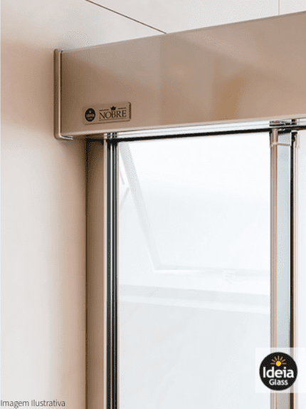 Box Nobre com amortecedor, com uma folha fixa e uma folha de correr, vidro temperado incolor com 08mm de espessura e kit reto de alumínio na cor Cromado, close no trilho superior e puxador asa.