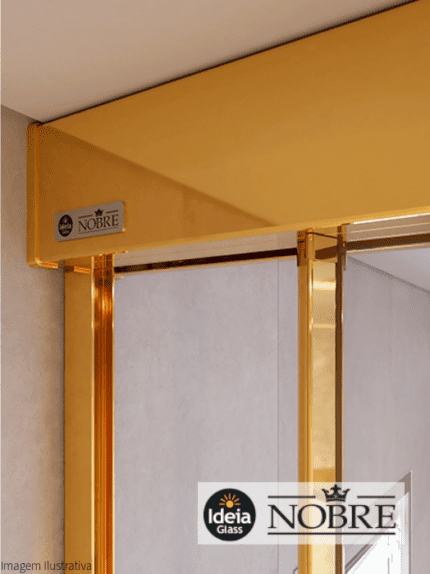 Box Nobre com amortecedor, com uma folha fixa e uma folha de correr, vidro temperado incolor com 08mm de espessura e kit reto de alumínio na cor Dourado, com close no trilho superior e puxador asa.